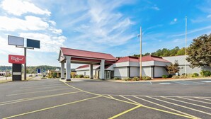 A Red Roof Inn with a spacious parking lot and a red-roofed building.