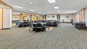 A large conference room with multiple tables and chairs, a patterned carpet, and a ceiling with recessed lighting. - Red Roof Inn Cambridge, OH (Cambridge)