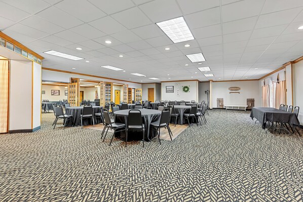 A large conference room with multiple tables and chairs, a patterned carpet, and a ceiling with recessed lighting. - Red Roof Inn Cambridge, OH (Cambridge)
