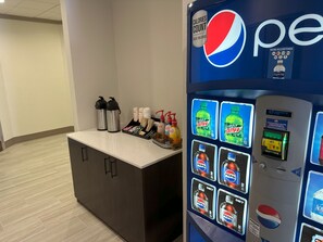 A vending machine with Pepsi and Mountain Dew options, a water dispenser, and a coffee station with disposable cups and utensils. - Red Roof Inn Cambridge, OH (Cambridge)