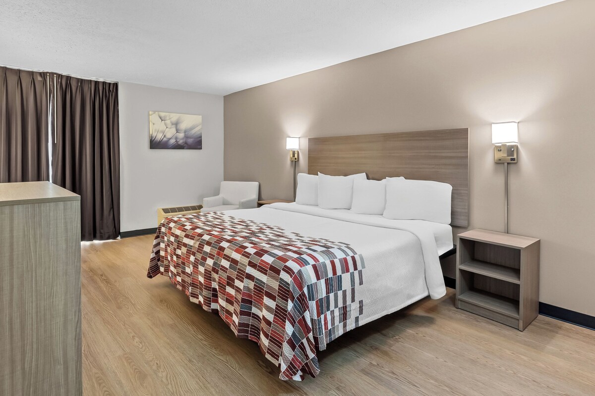 Ein Hotelzimmer mit einem großen Bett, zwei Nachttischen, einer Wandlampe und einem Bild an der Wand.
