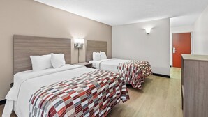 A hotel room with two beds, each with a different style of bedding, a nightstand, a lamp, and a wooden wardrobe. - Red Roof Inn Cambridge, OH (Cambridge)