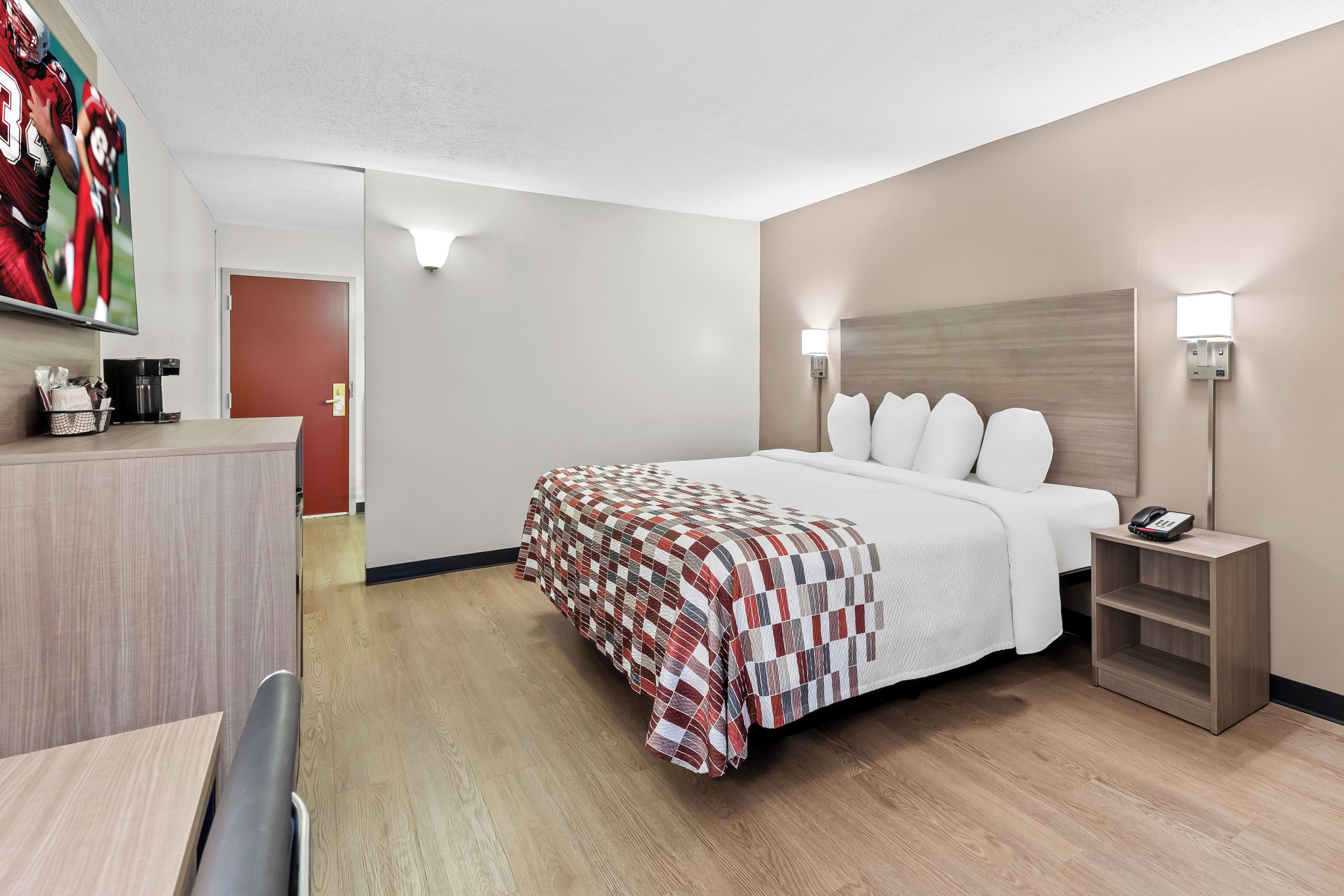 Una habitación de hotel con cama, mesita de noche y escritorio con silla.
