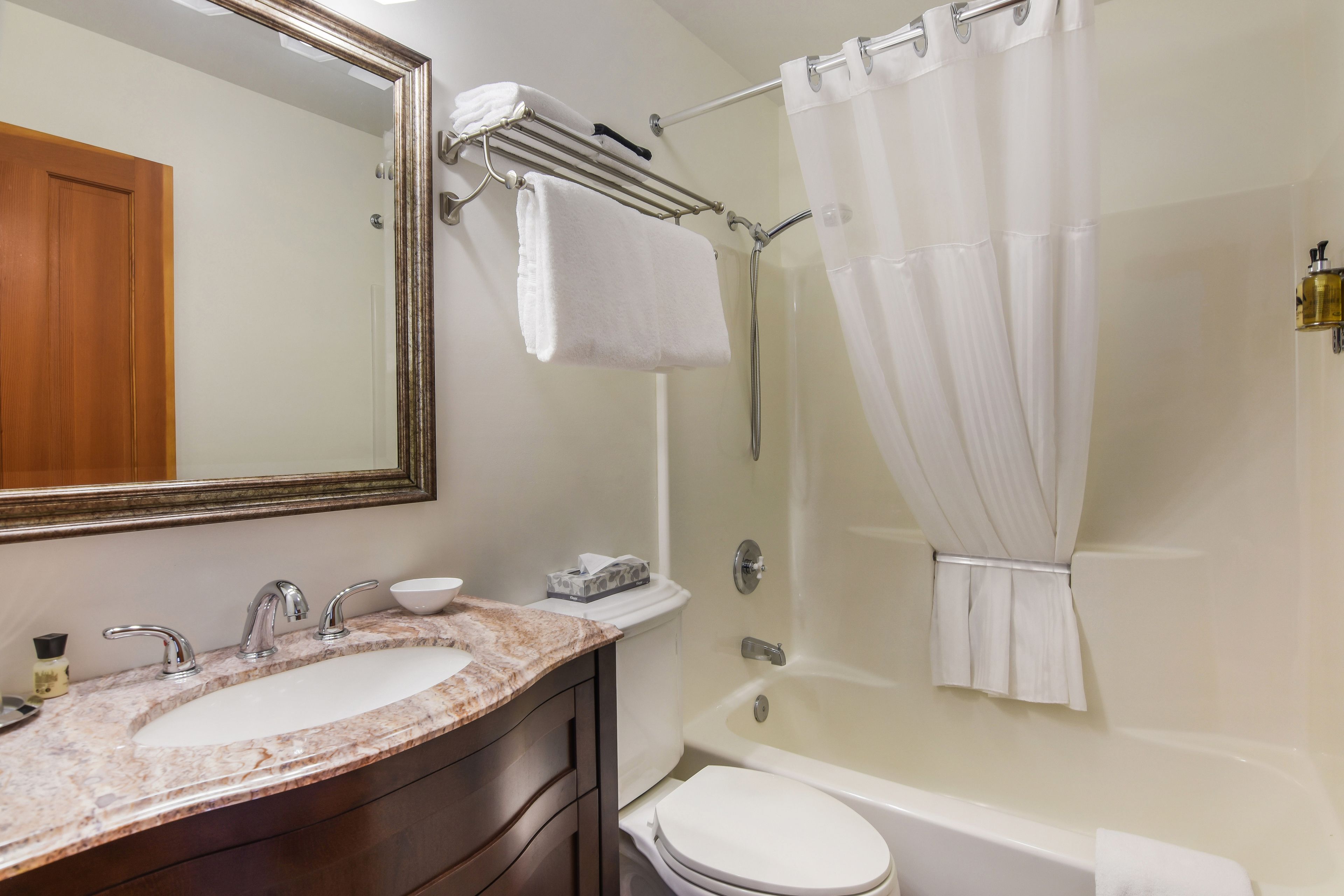 Une salle de bain avec un lavabo en marbre, des toilettes, une baignoire et un rideau de douche.