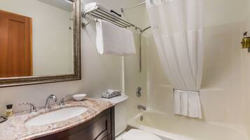 Une salle de bain avec un lavabo en marbre, des toilettes, une baignoire et un rideau de douche.