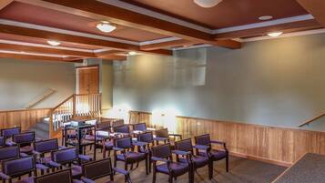 A conference room with rows of chairs, a wooden staircase, and a door marked "EXIT".
