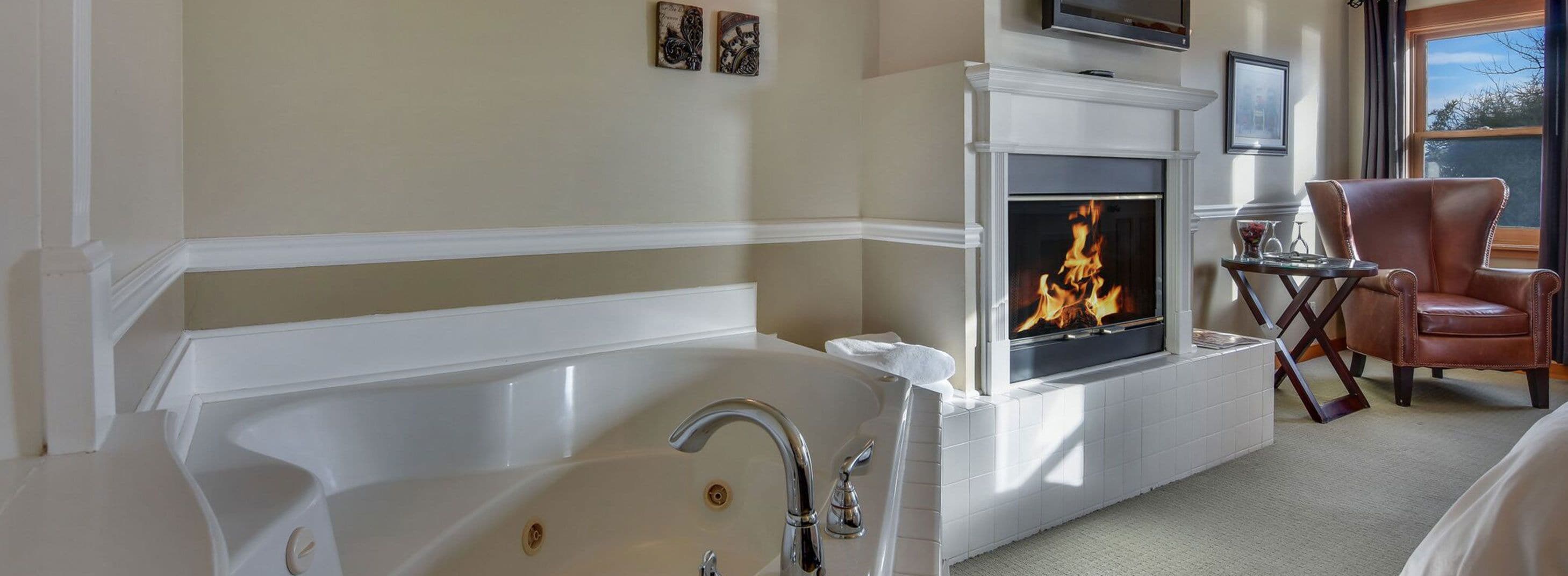 Une salle de bain avec une grande baignoire, une cheminée et un fauteuil en cuir.