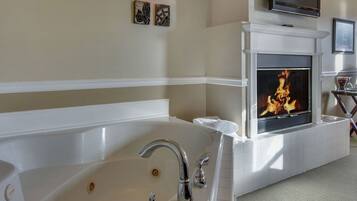 Une salle de bain avec une grande baignoire, une cheminée et un fauteuil en cuir.