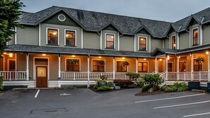 A two-story building with a porch, multiple windows, and hanging flower baskets. - The Wild Iris Inn (La Conner)