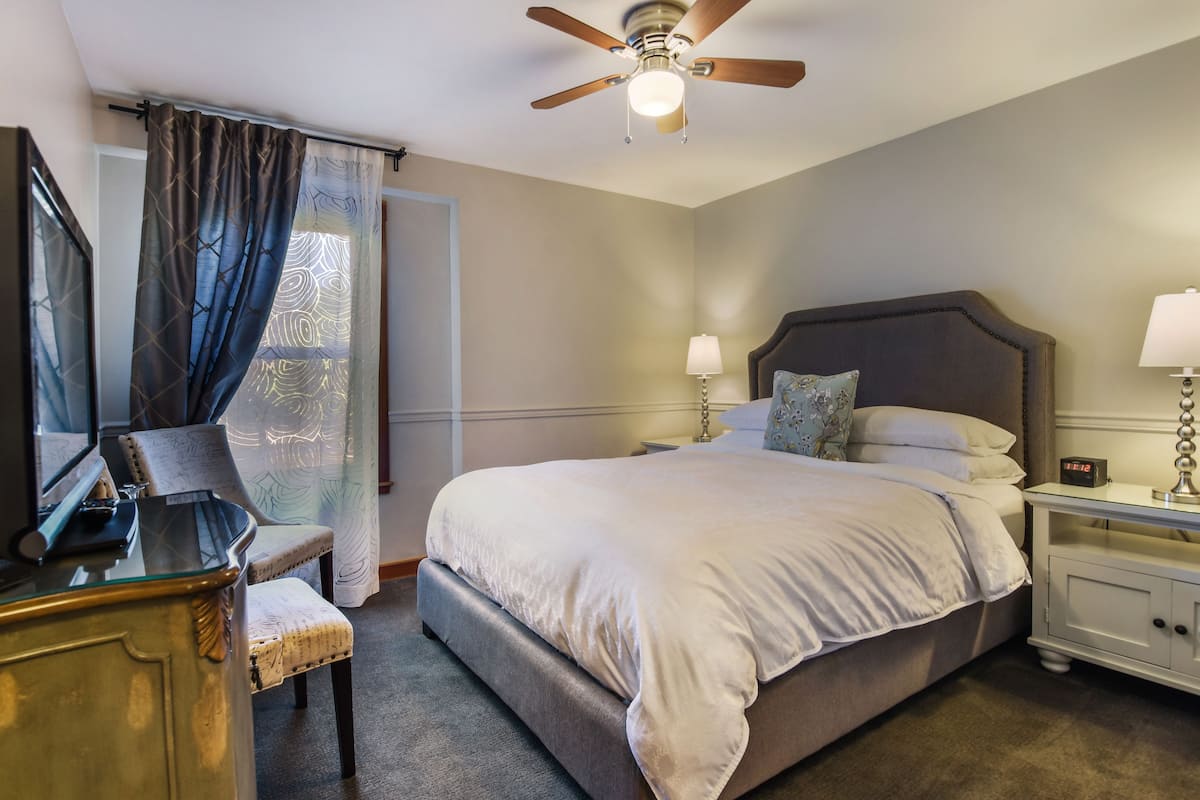A bedroom with a bed, nightstands, a desk, and a chair.