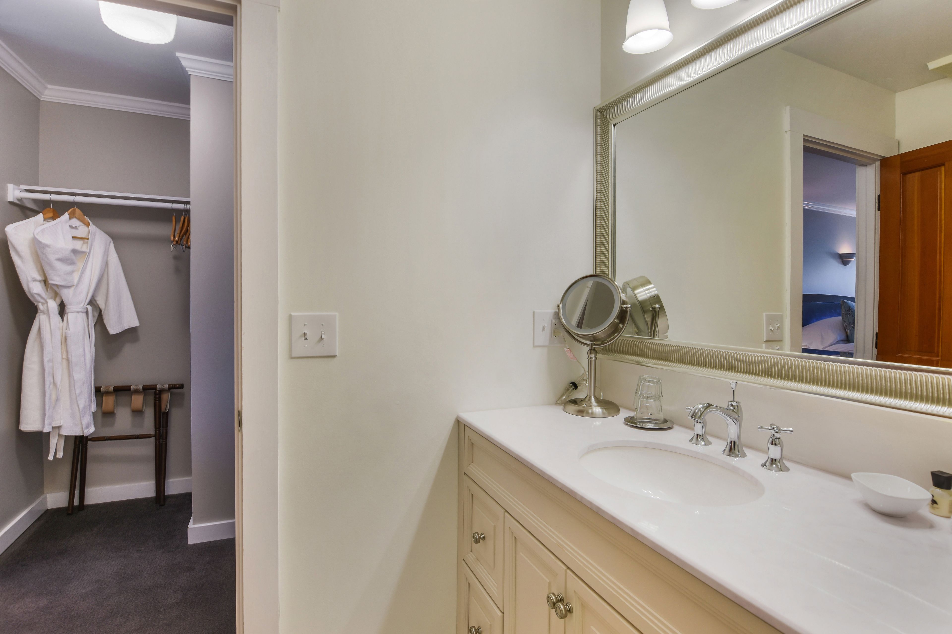 A bathroom with a white sink, a large mirror, and a towel rack.