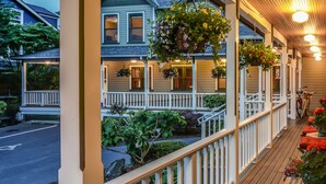 A covered porch with hanging flower baskets and a wooden railing. - The Wild Iris Inn (La Conner)