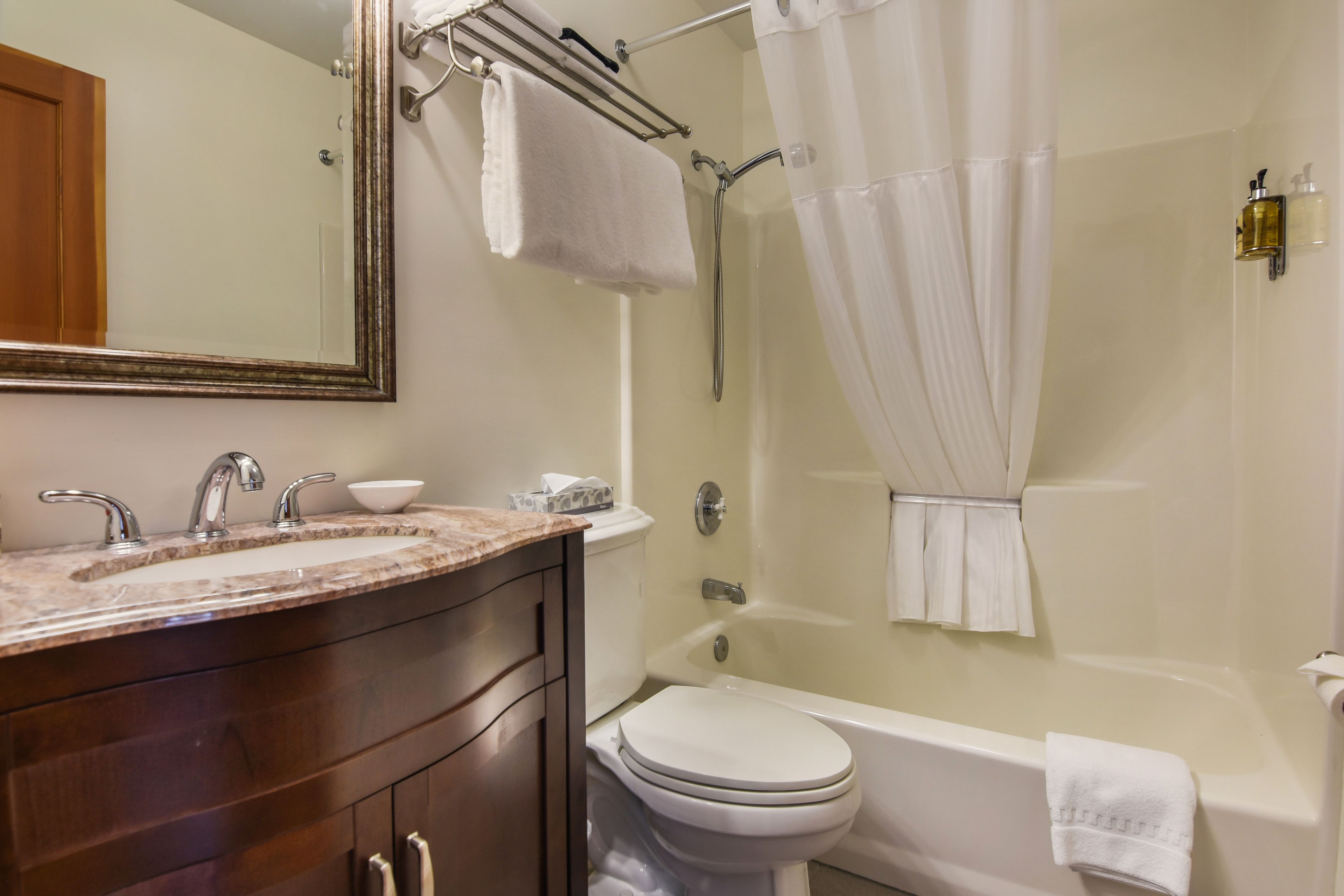 A bathroom with a sink, mirror, toilet, and bathtub.
