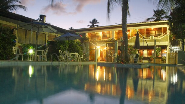 Piscina con el reflejo de un edificio y palmeras.