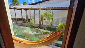 Una hamaca en una habitación iluminada por el sol, con vistas a un jardín y un edificio.