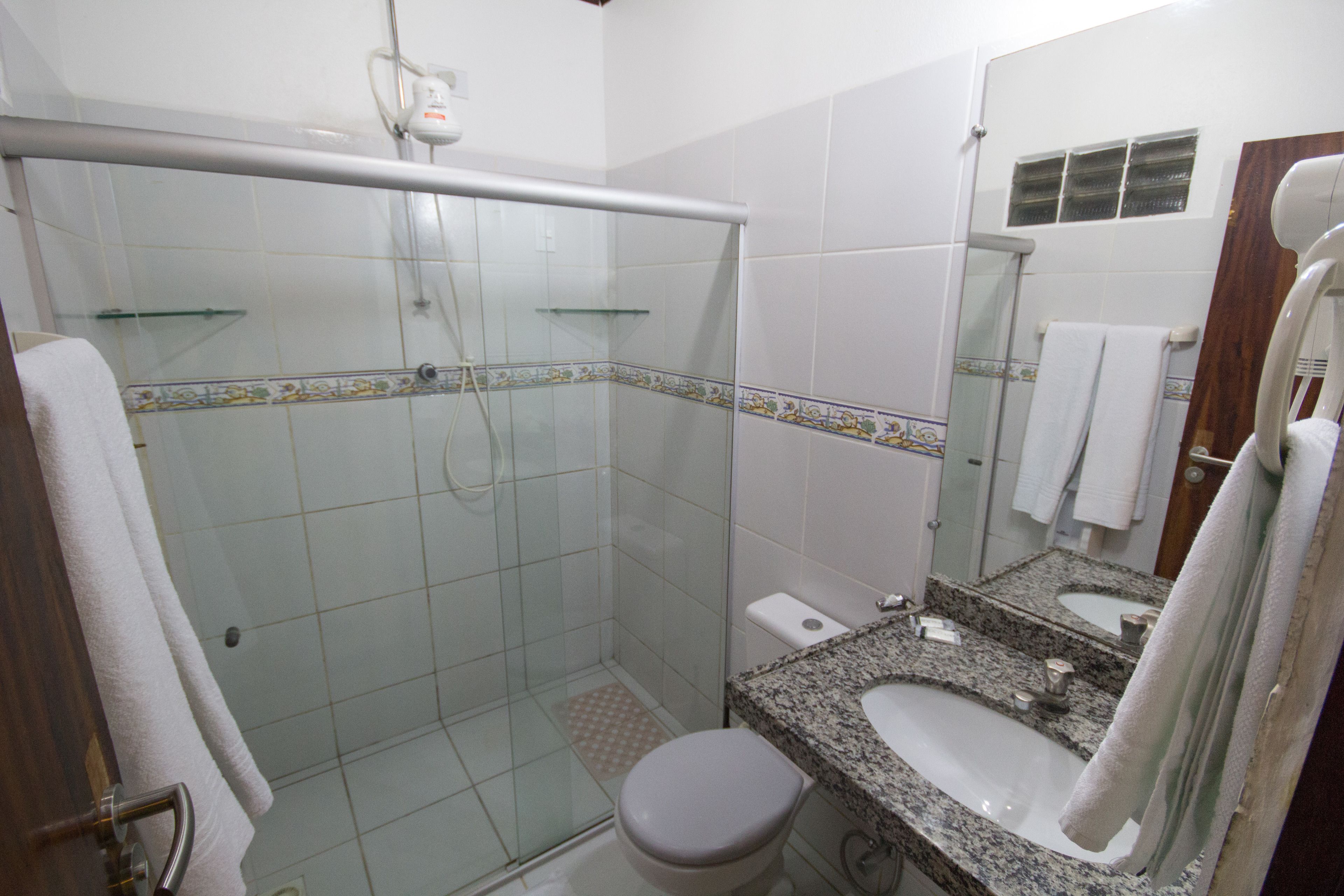 Un baño con ducha de vidrio, inodoro, lavabo y espejo.