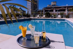 A poolside setting with lounge chairs and a tray of drinks.