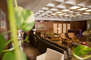 A hotel lobby with a seating area, a reception desk, and a framed artwork on the wall.
