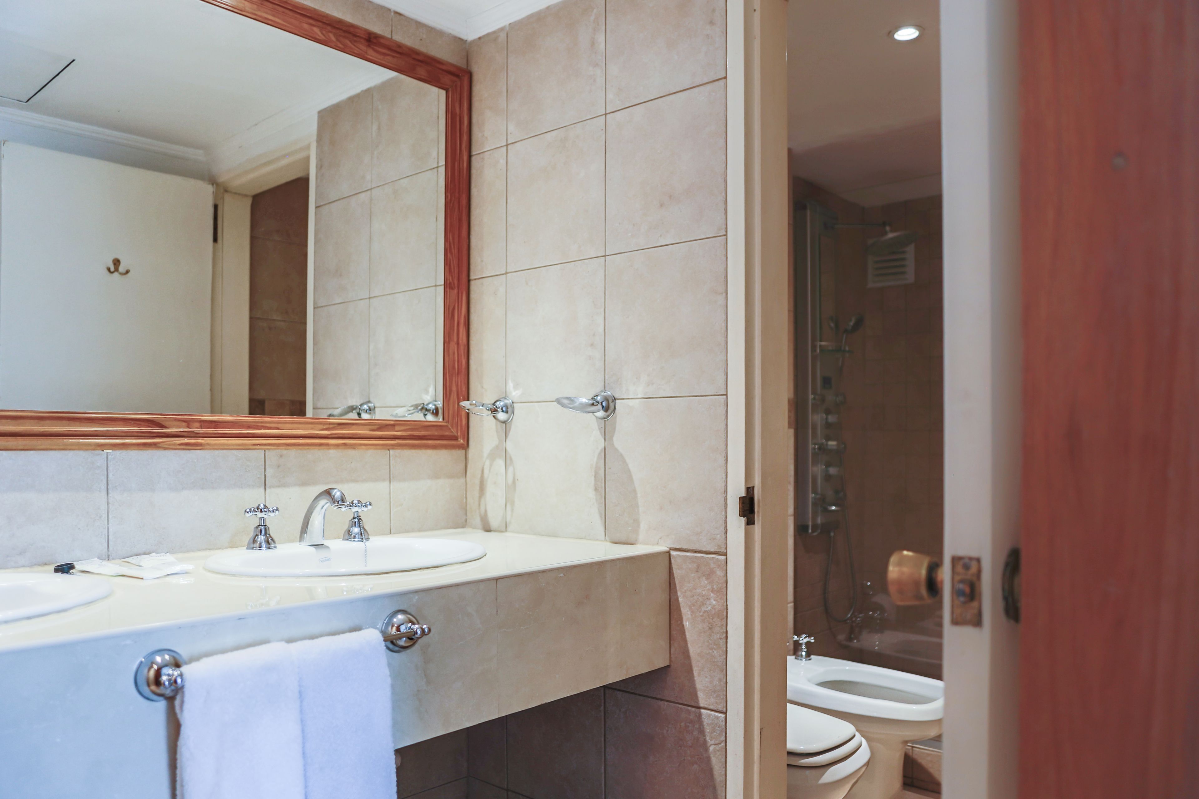 Un baño con un espejo grande, dos lavamanos y una zona de ducha.