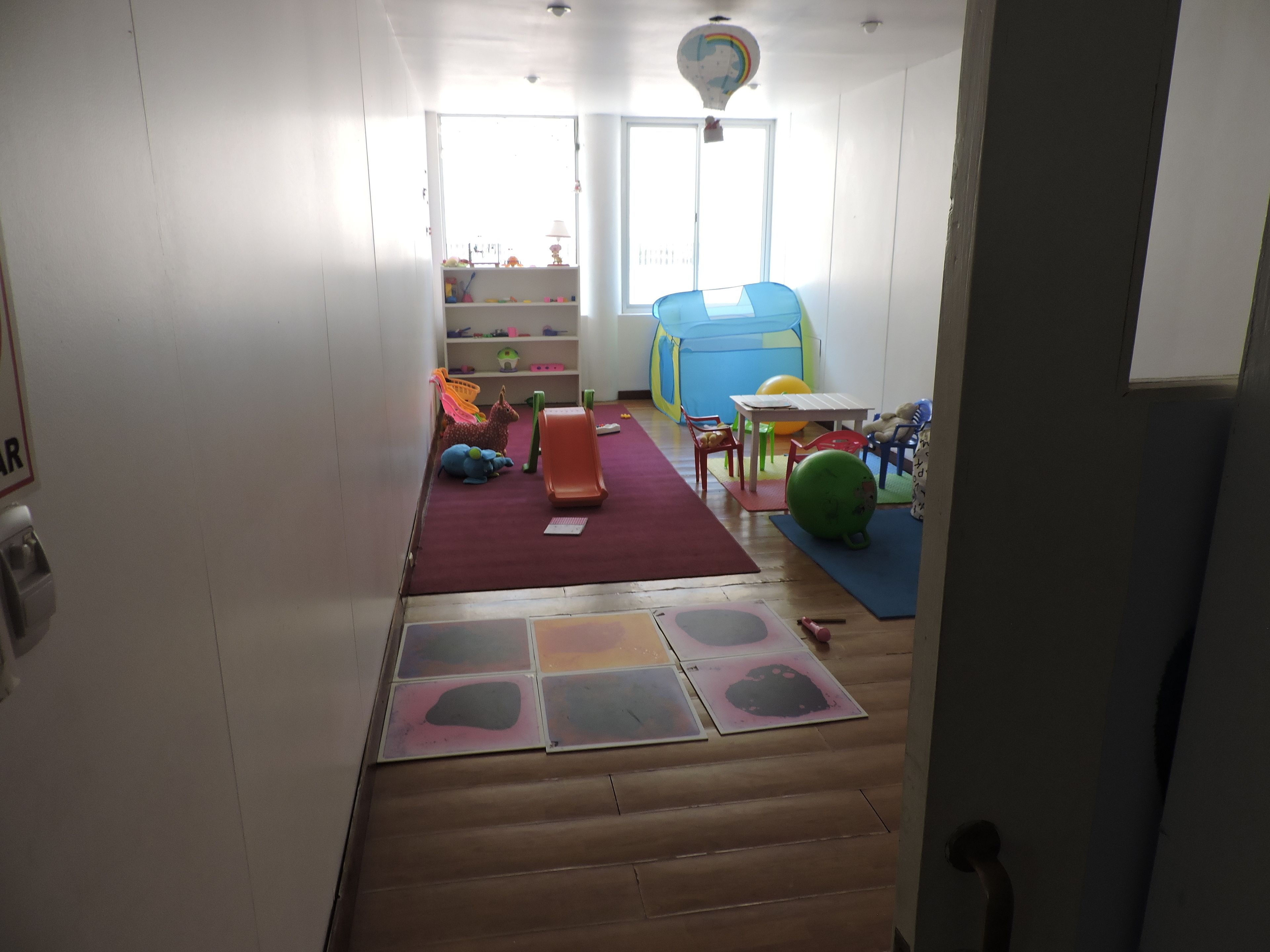 A room with a play area including a slide, colorful mats, and toys.