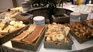 A buffet with various food items including bread, pastries, and a variety of dishes. - Julio Cesar Hotel (Posadas)