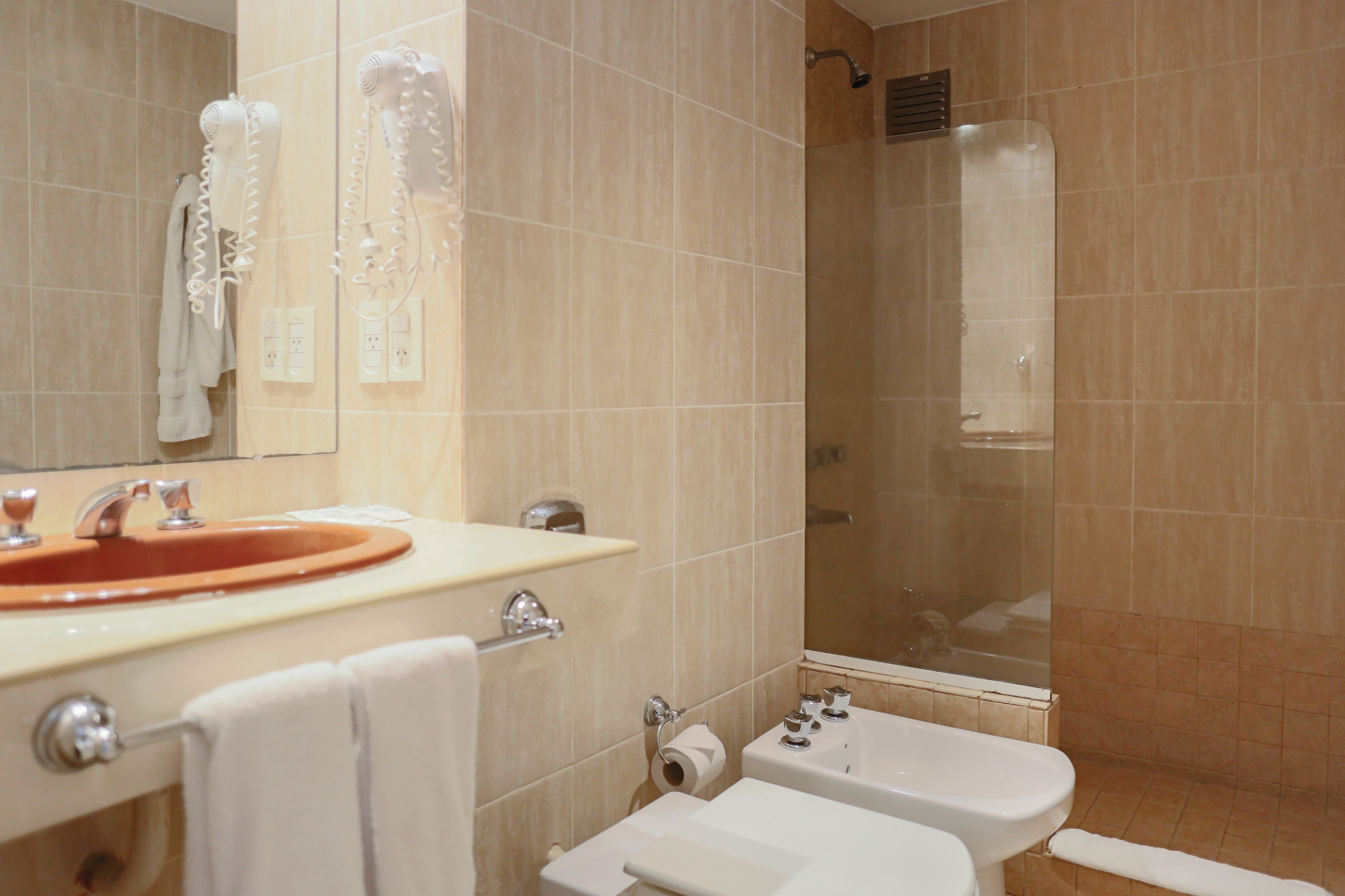 A bathroom with a sink, mirror, towel rack, and shower.