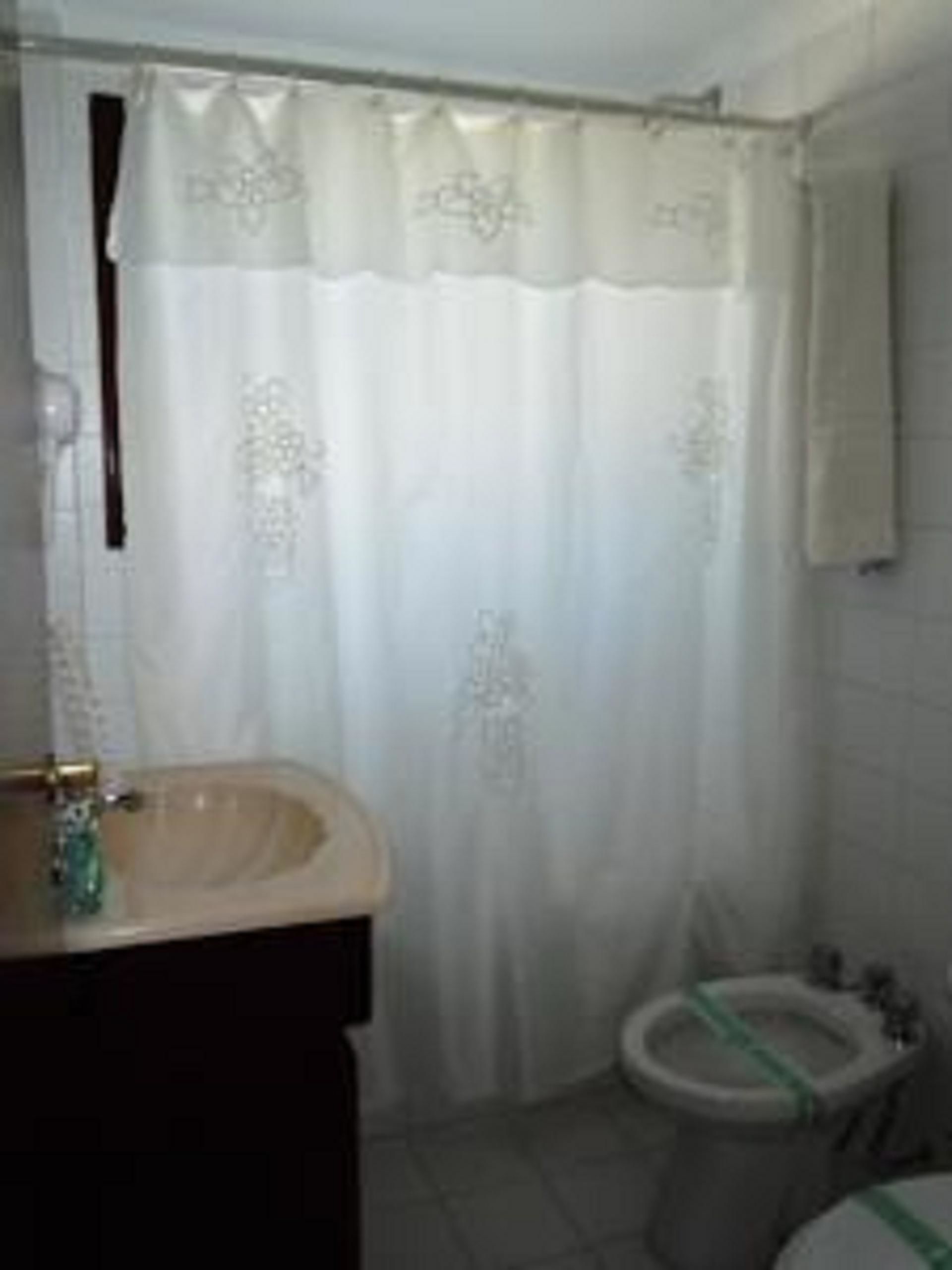 Casa de banho com lavatório, sanita e cortina de chuveiro.