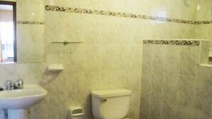 Casa de banho com lavatório, sanita e dispensador de toalhas.