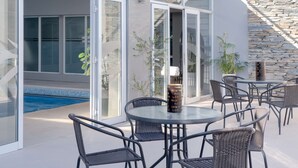A modern outdoor patio with a pool, glass doors, and outdoor seating. - NH Santiago del Estero (Santiago del Estero)