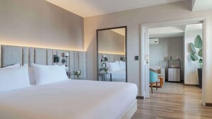 A modern hotel room with a large bed, a bedside table with a lamp, a mirror, and a view into a connected bathroom. - NH Santiago del Estero (Santiago del Estero)