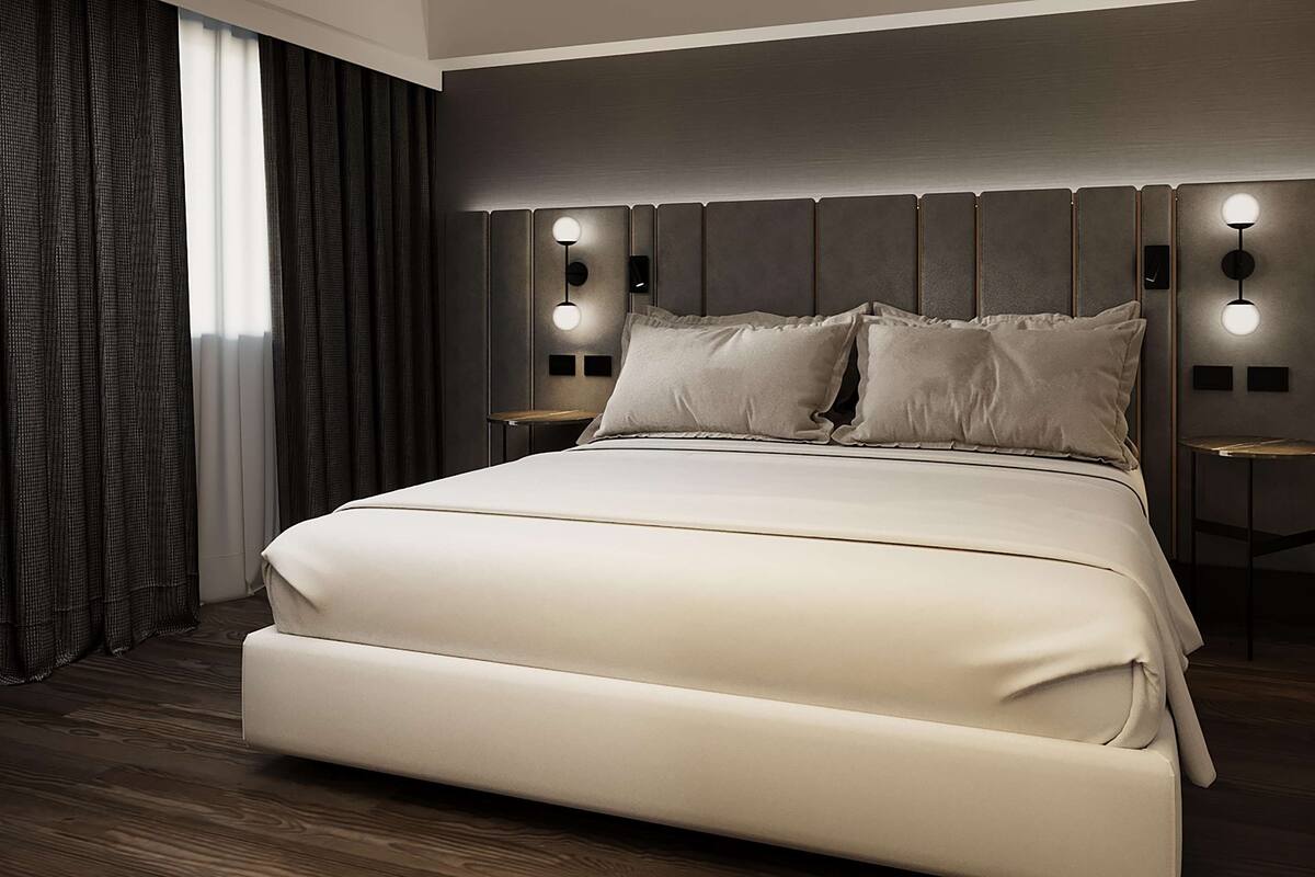 Ein modernes Schlafzimmer mit einem großen Bett, einem dunklen Kopfteil und zwei Nachttischen mit Wandleuchten.