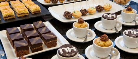 A variety of desserts including cakes, cookies, and pastries on a buffet table.
