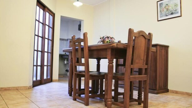 Een eetruimte met een houten tafel, stoelen, een kast en een deur naar een andere kamer.
