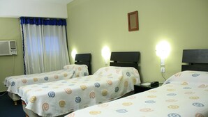 Een hotelkamer met twee eenpersoonsbedden, een raam met gordijnen, een airconditioning en wandlampen.