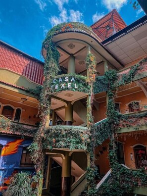 Un edificio de varios pisos con un atrio central, balcones y un letrero que dice 'CASA FEXEL'.