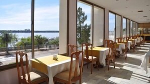 A restaurant with tables and chairs arranged along a balcony overlooking a body of water. - Quirinale Hotel (Colon)