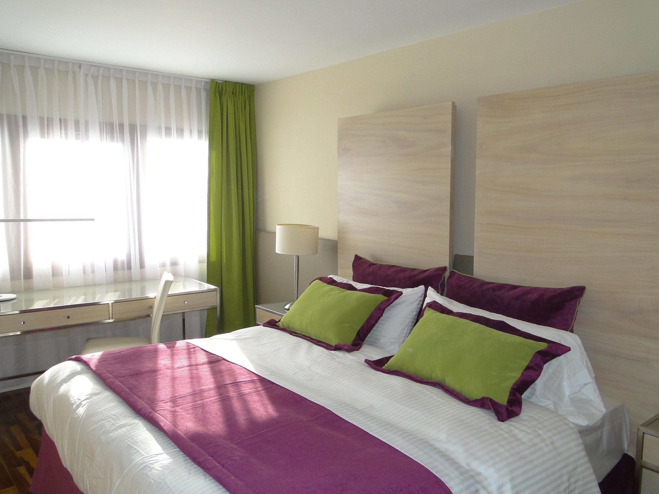 Una habitación de hotel con una cama, un escritorio y una silla.