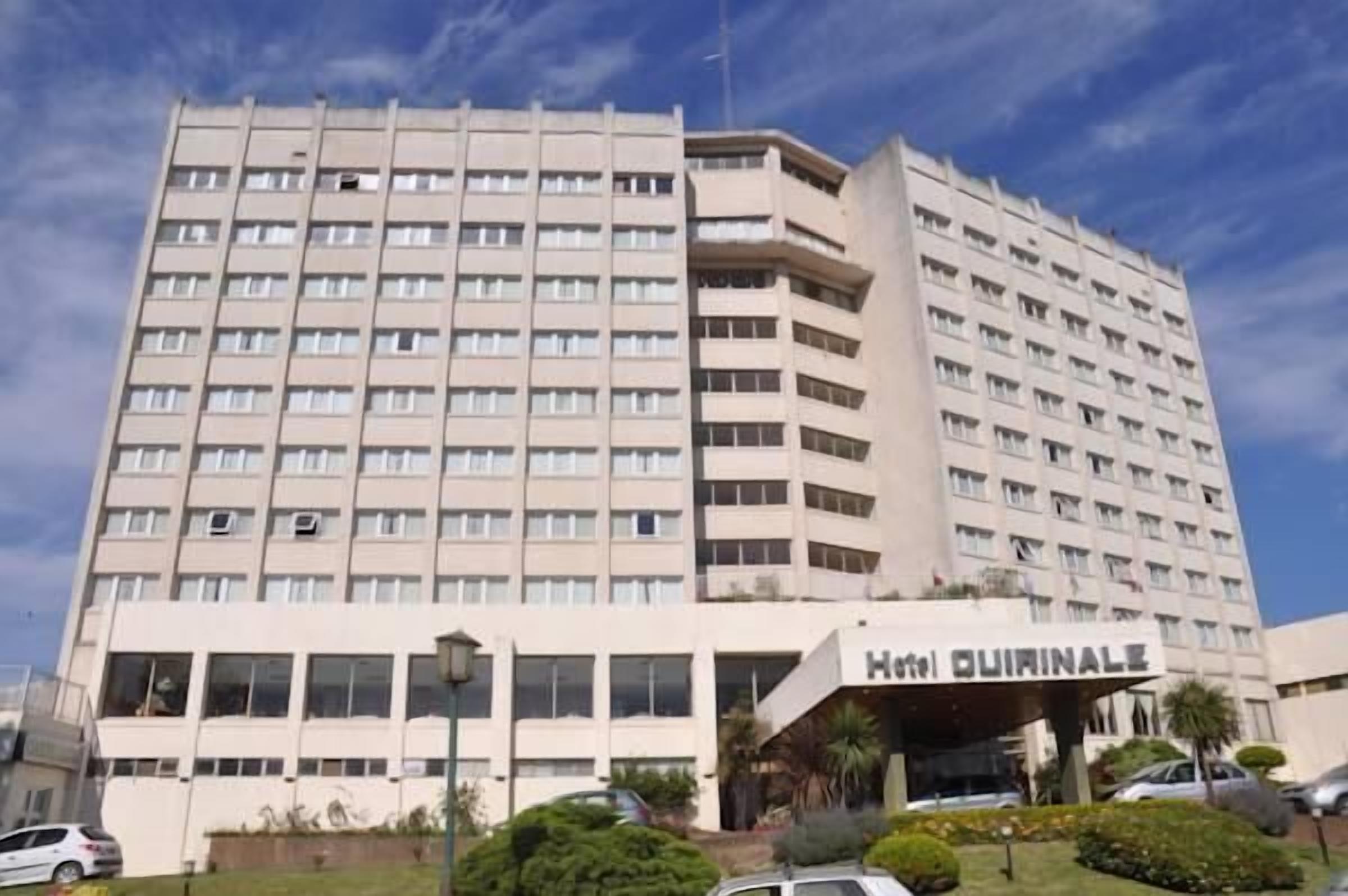 A multi-story hotel with a flat facade and a prominent entrance labeled "Hotel Quirinale."