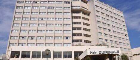A multi-story hotel with a flat facade and a prominent entrance labeled "Hotel Quirinale."