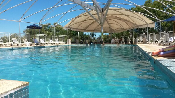 A swimming pool with clear blue water, surrounded by lounge chairs and umbrellas. - Quirinale Hotel (Colon)