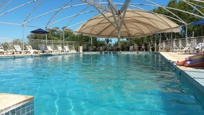 A swimming pool with clear blue water, surrounded by lounge chairs and umbrellas. - Quirinale Hotel (Colon)