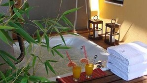 Une salle de bain avec une baignoire, deux verres de jus d’orange et une pile de serviettes blanches.
