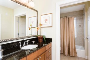 A bathroom with a sink, mirror, framed artwork, and a shower curtain. - RVH 052 Relax in Centre Court (Kissimmee)