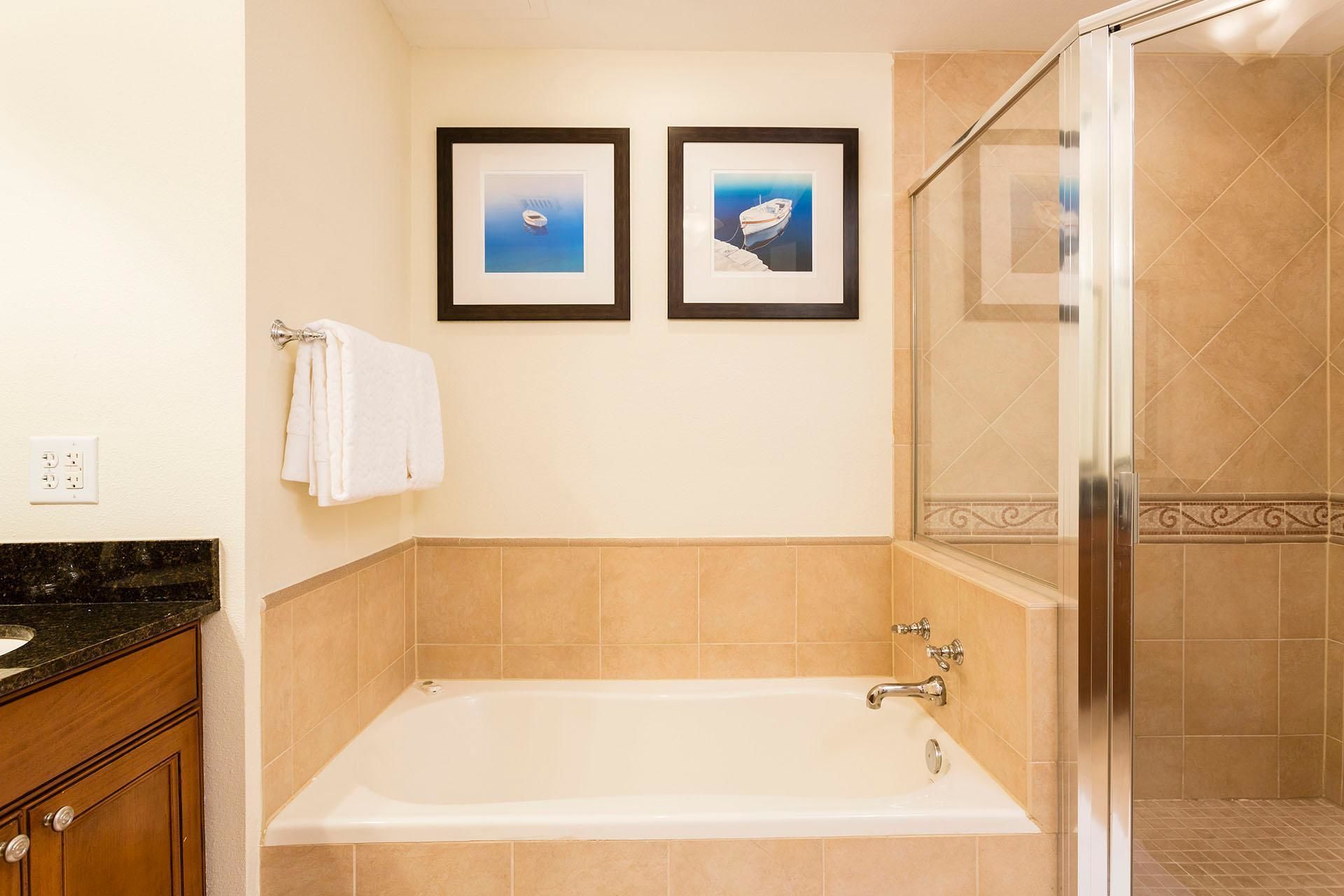 Ein Badezimmer mit einer Badewanne, einer Dusche und zwei gerahmten Bildern an der Wand.