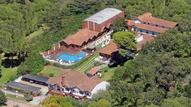 Vista aérea de un resort con piscina, varias construcciones y abundante vegetación.