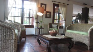 Una sala de estar acogedora con mobiliario de mimbre, una mesa de centro de madera y una lámpara.