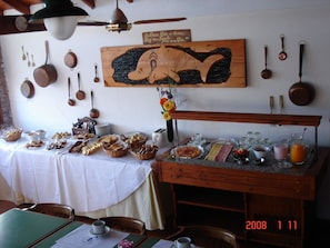 Ein Frühstücksbuffet mit verschiedenen Backwaren und Getränken, Holzgeschirr an der Wand und ein Schild im Vintage-Stil.