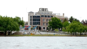 Een hotel aan het water met een modern ontwerp, met een opvallende glazen gevel en een trap naar de ingang.