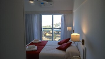 Habitación de hotel con cama, lámpara de noche, teléfono y vista por la ventana.