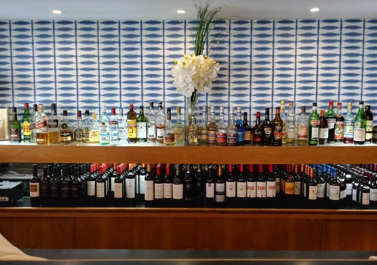 Un bar con una variedad de botellas de licor y un arreglo floral blanco decorativo.